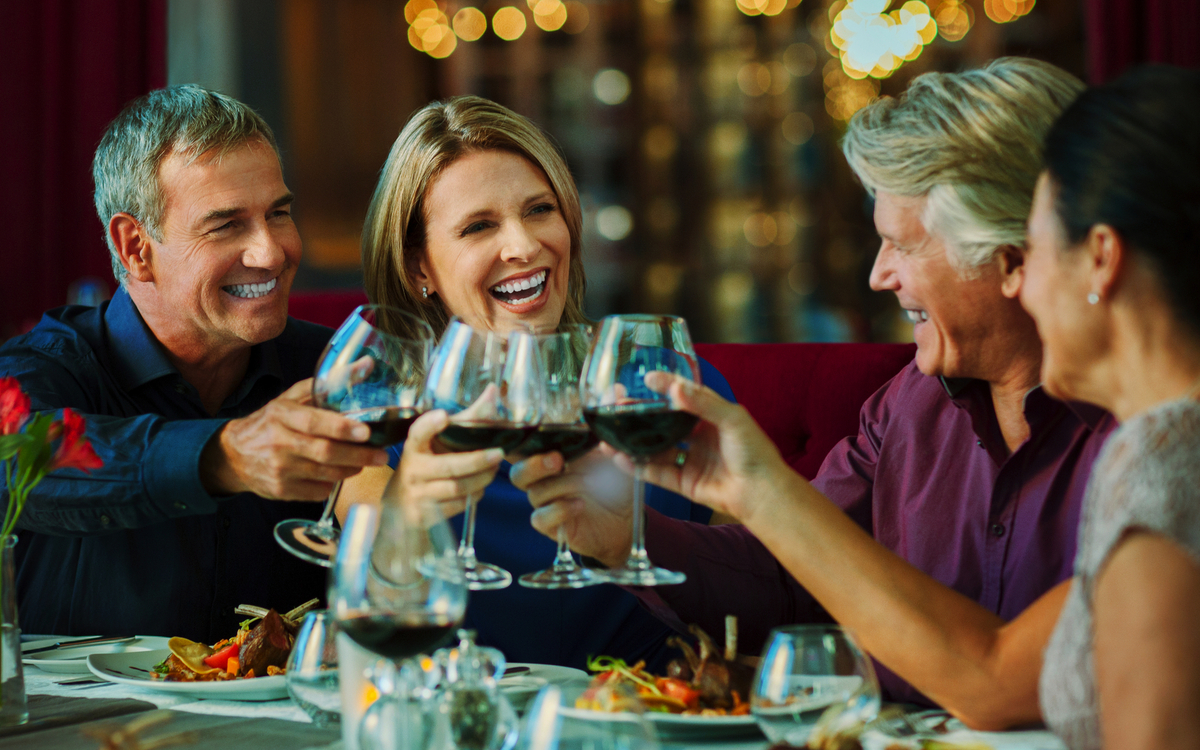 Menschen stoßen im Restaurant mit Rotwein an